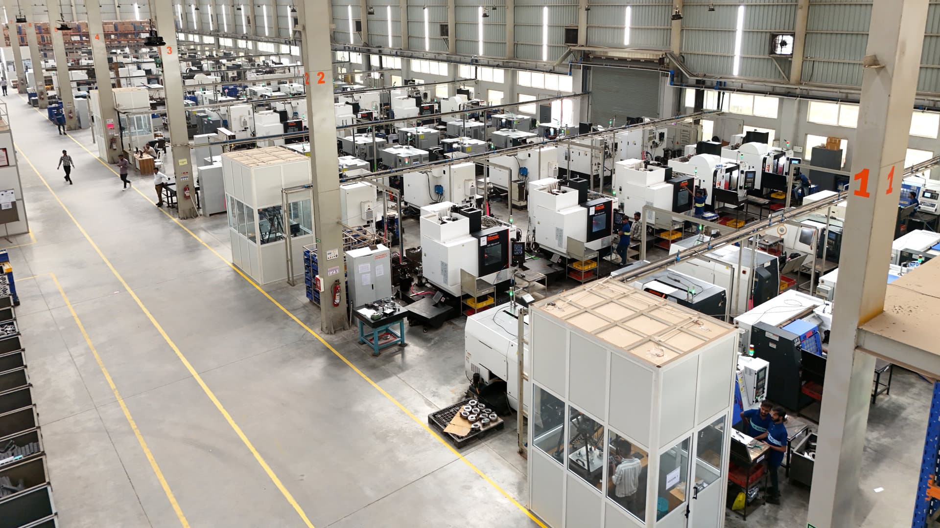 Wide CNC factory floor with multiple machining centres and operators